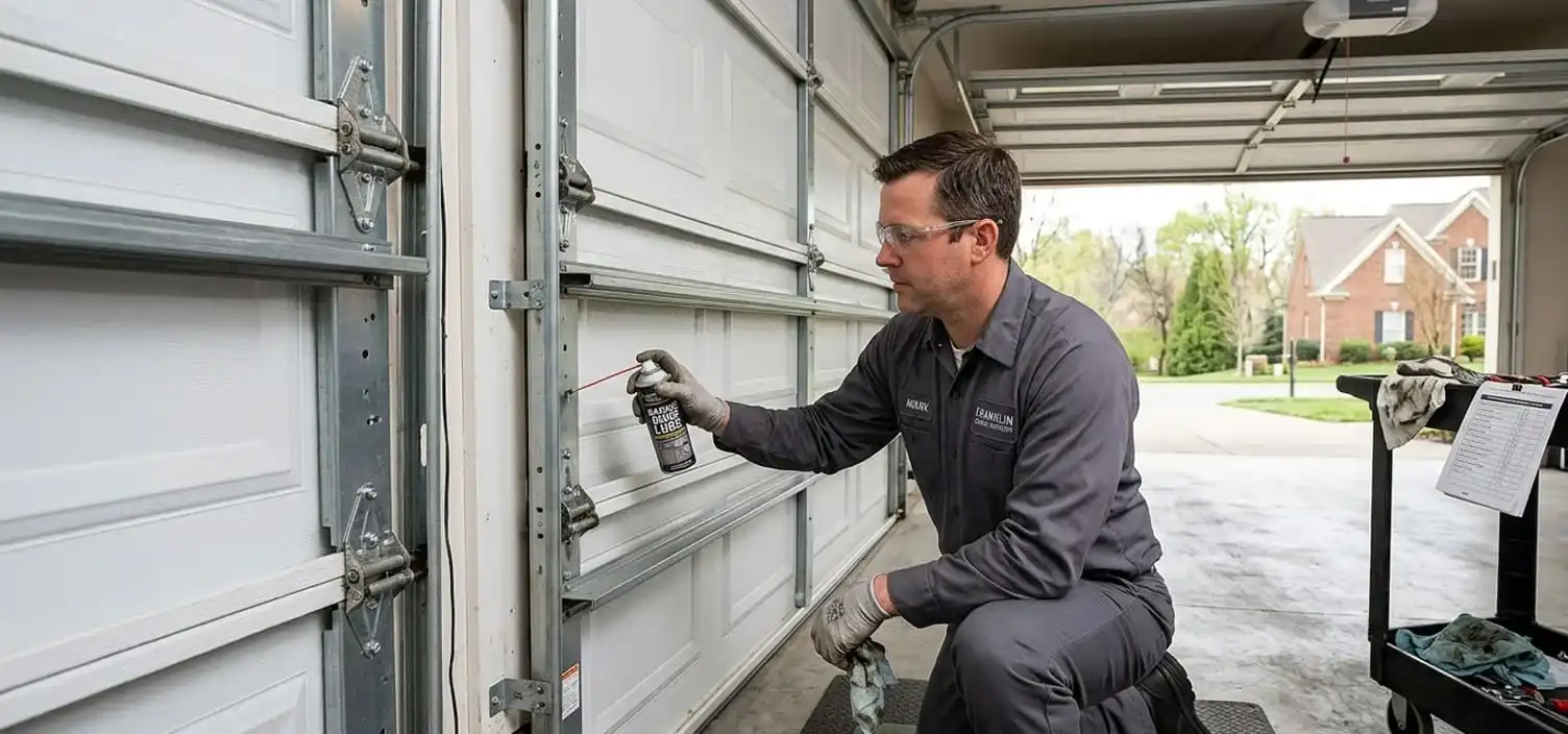Technician lubricating garage door rollers and hinges at a Franklin Tennessee home during a maintenance visit